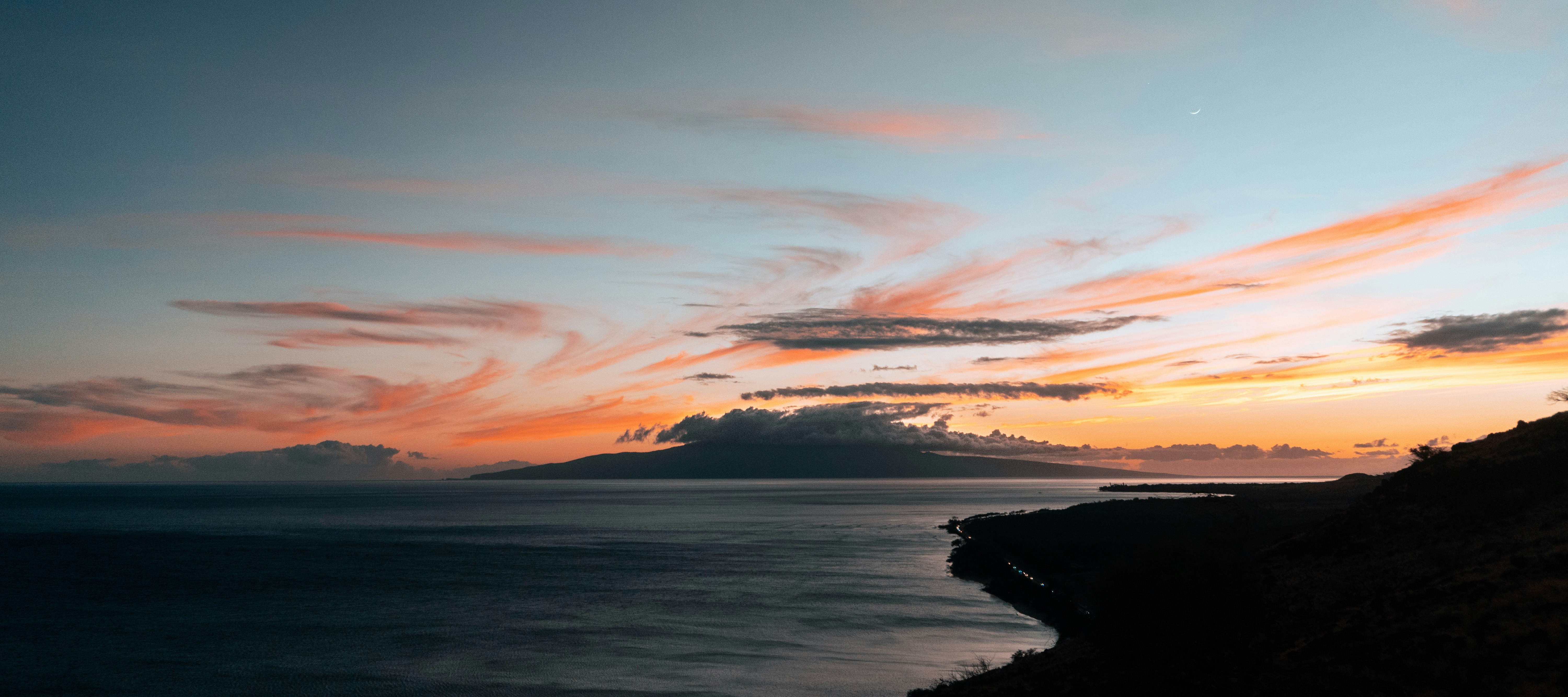 body of water under cloudy sky during sunset